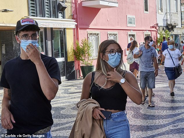On Friday, Portugal reported its highest new daily virus figure for seven weeks, with 401 cases detected (tourists wearing masks in a busy tourist street, pictured)