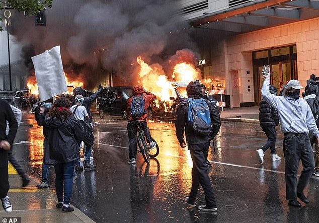 People caught rioting during large protests could be stripped of their federal unemployment benefits and be forced to pay an order of restitution to police under a new bill proposed by a Republican Congressman. Pictured: Rioters setting fire to vehicles in Seattle on May 30