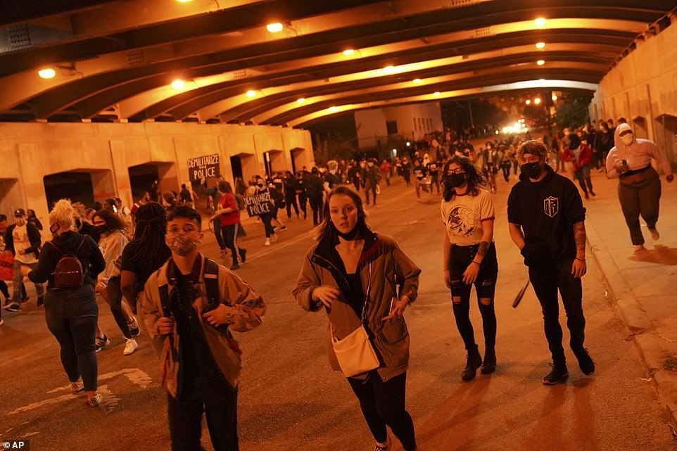 A crowd is seen marching through an underpass after the 9pm curfew went into effect in Louisville