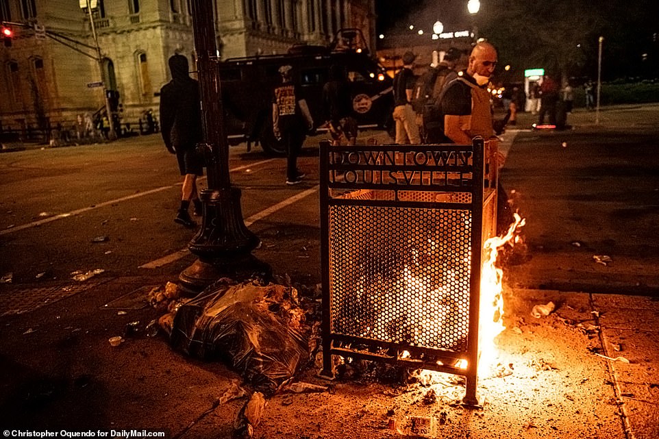 Protesters pass by a burning pile of trash as tensions boiled over in Louisville's downtown area on Wednesday night