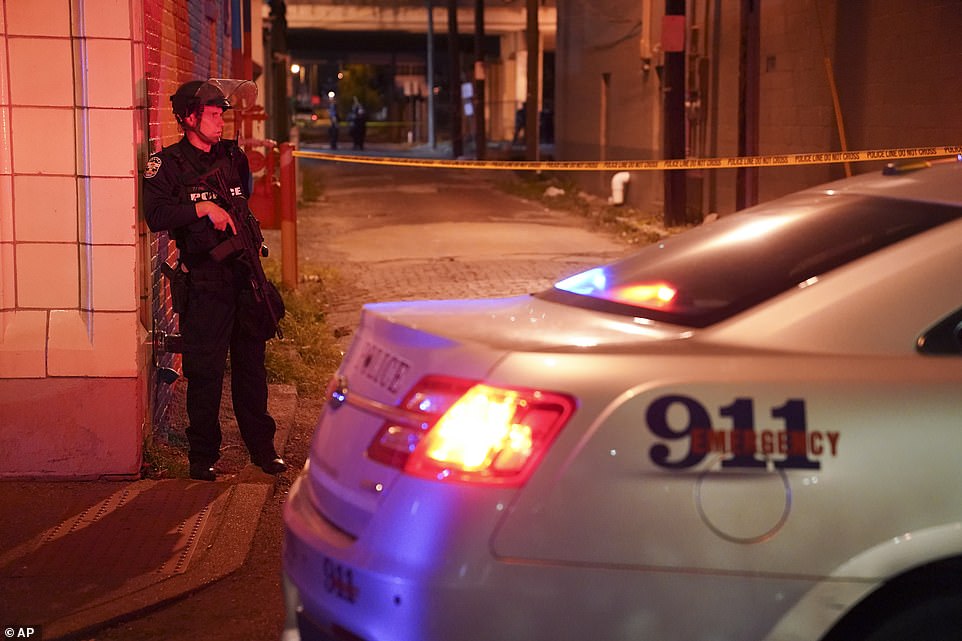 A police officer stands in an alley after an officer was shot on Wednesday evening