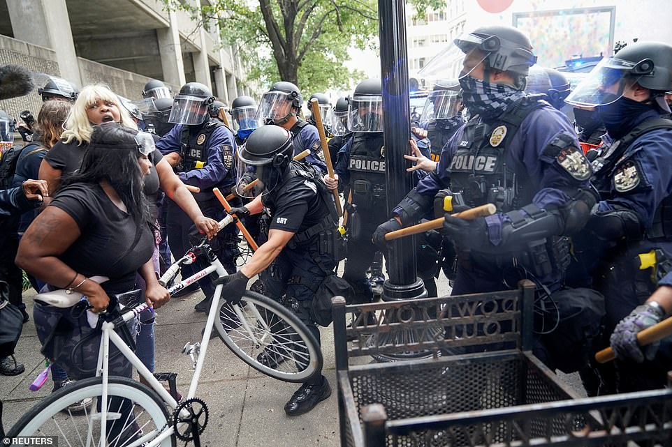 A woman screams as a police officer attempts to take a bike away from her during clashes between cops and protesters