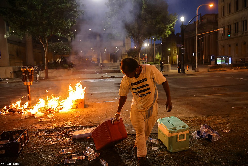 A man removes a cooler box with water after protesters set fire in front of the Louis D Brandeis Hall of Justice