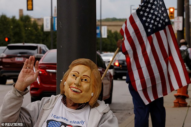 A demonstrator wearing a mask of former U.S. Secretary of State Hillary Clinton sits outside the first presidential debate
