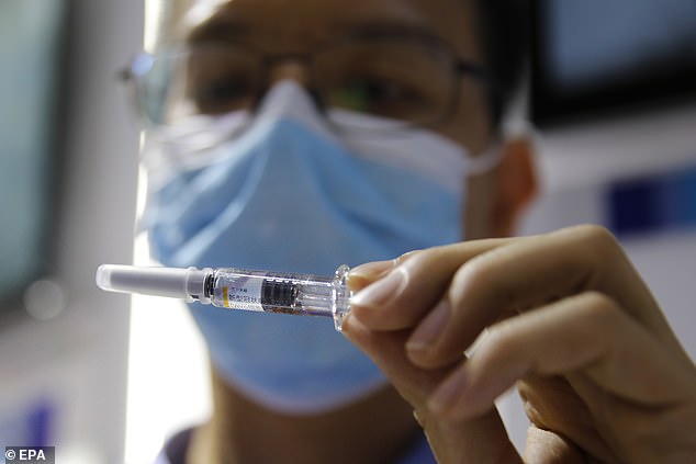 Hundreds of thousands of Chinese citizens have received experimental COVID-19 vaccines under a government emergency scheme while reporting no cases of infection, a state-owned drug firm has claimed. The file picture shows a staff member holding a COVID-19 coronavirus vaccine candidate at Sinovac Biotech Ltd stand at a trade fair in Beijing on Saturday