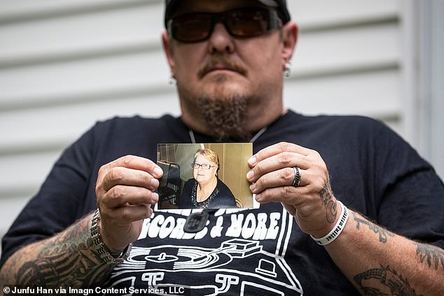 Dennis Williams pictured holding an image of his mother, 68, who passed away after contracting coronavirus while living at the Villages of Lapeer nursing home