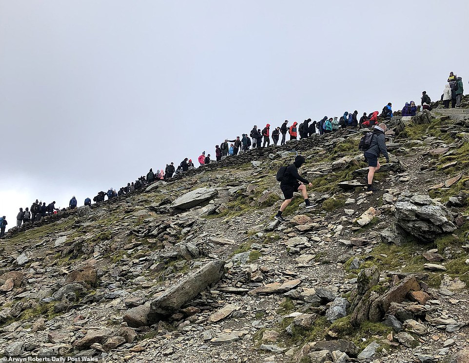 Hundreds of walkers cram onto Snowdon and queue without social distancing for a photo at the summit