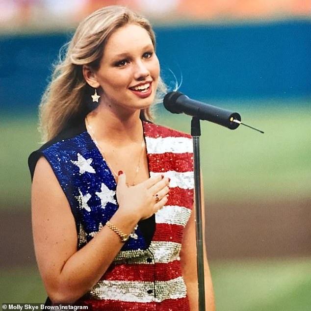 Brown is seen singing the National Anthem at a Miami Dolphins game when she was a teen