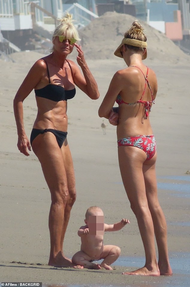 Playful: Meanwhile, his wife Jennifer chatted near the water with their daughter and the young girl near their feet