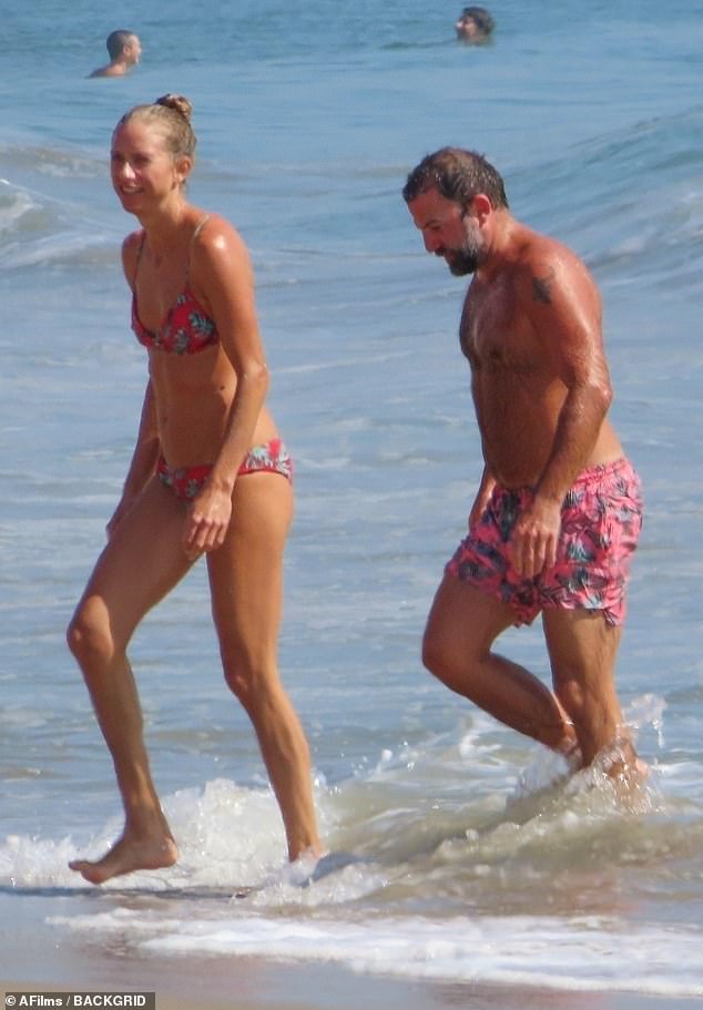 Matching: One of Joe's daughters hit the waves with her partner, donning matching pink swimsuits
