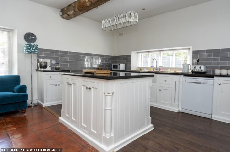 There's ample space in this large kitchen with a central island and exposed beams.  It offers plenty of space for the whole family to spread out in as well as a convenient place for guests to mingle in