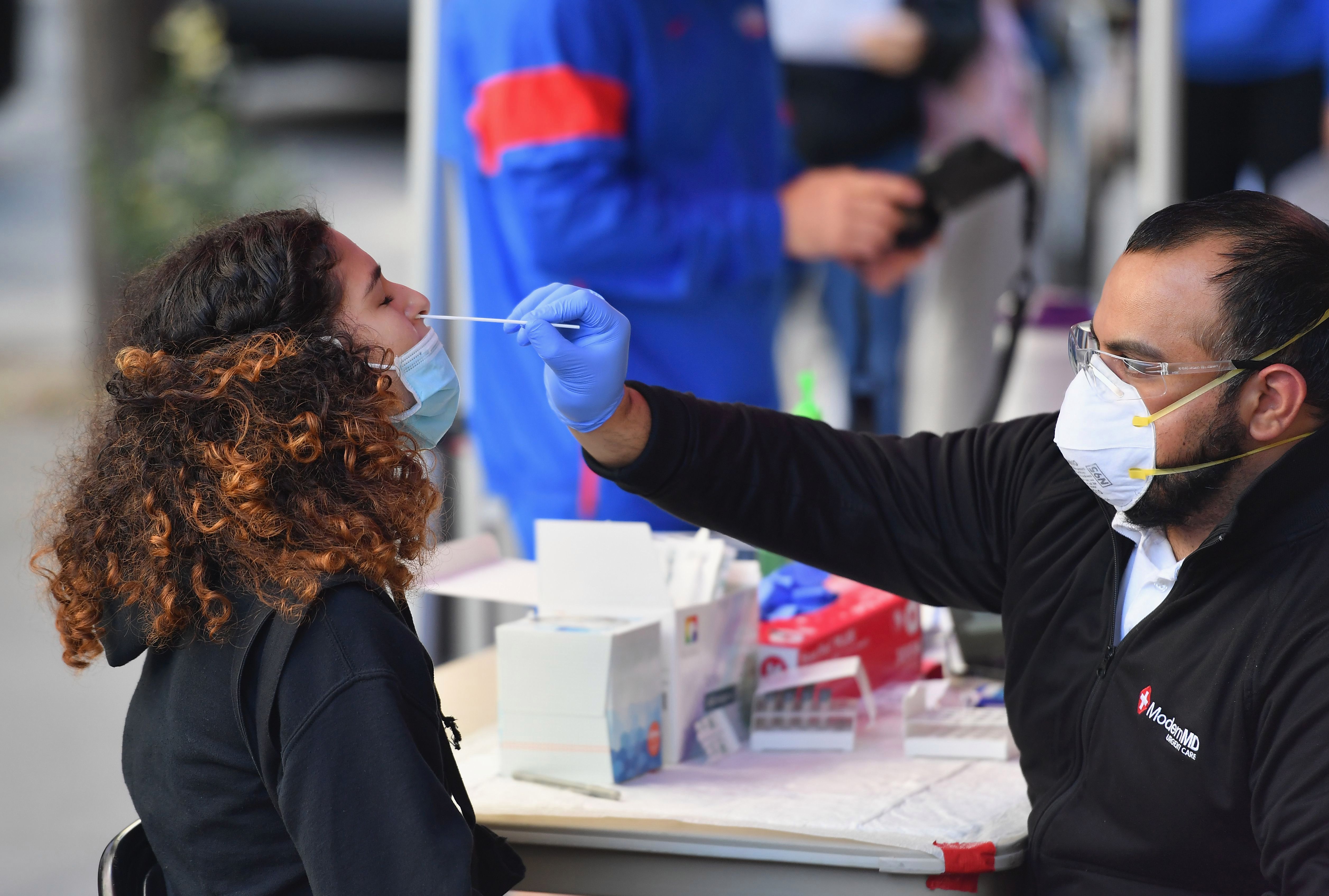 A health worker takes a nasal sample for a PCR test from a student in New York.