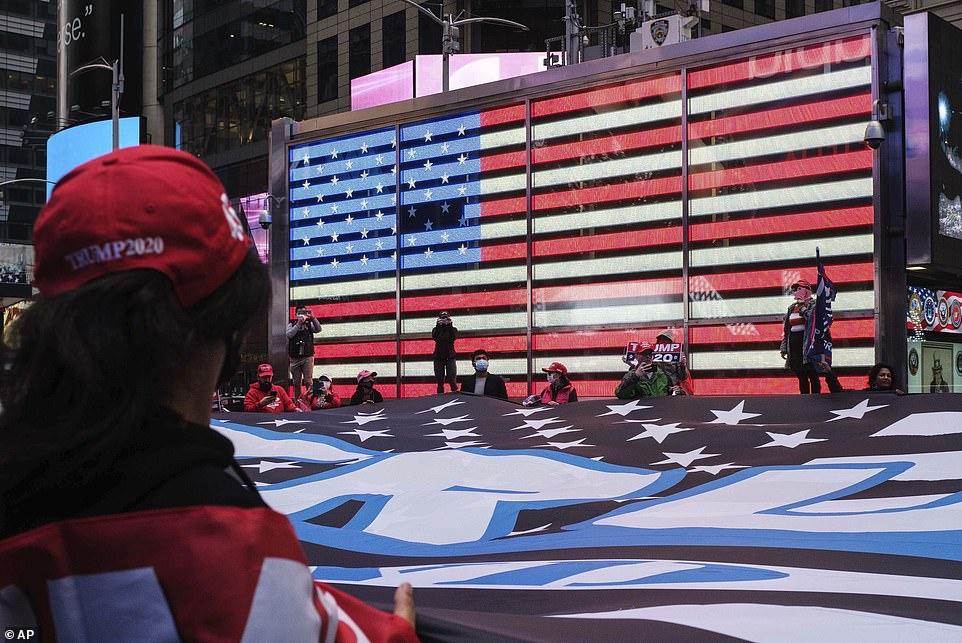 Supporters of President Donald Trump pause at Times Square Tuesday with a 75ft by 50ft flag