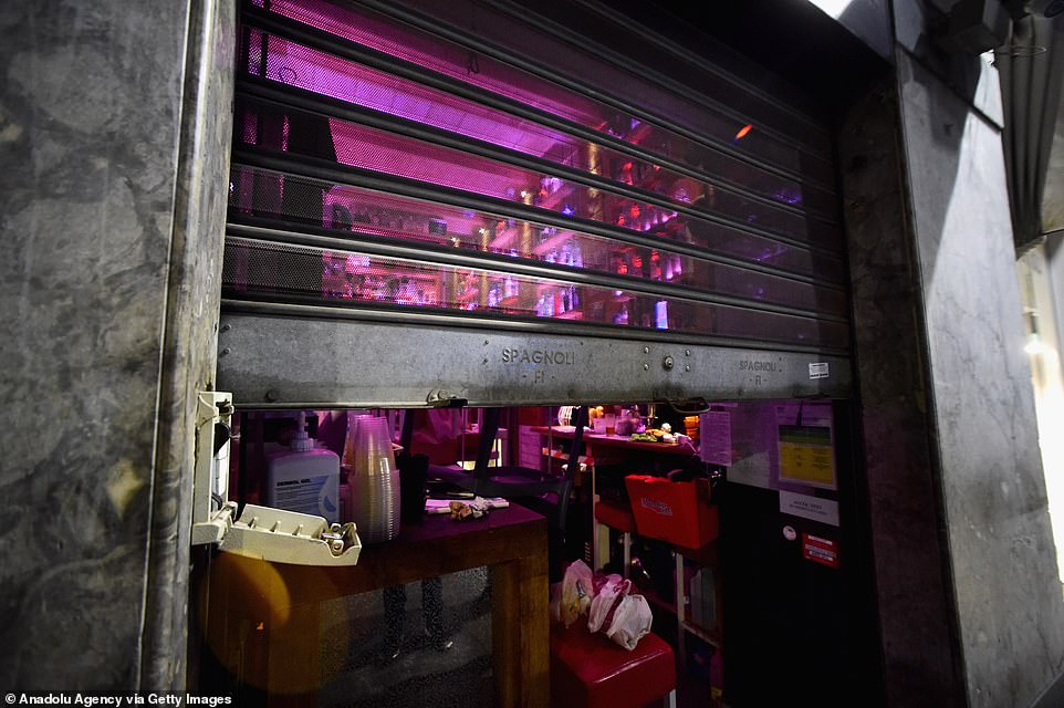 A bar owner lowers the shutter at 11pm because of the curfew order which will run at least into mid-November