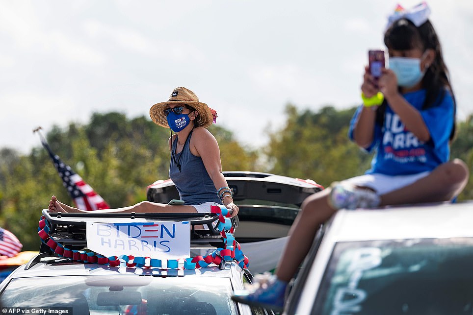 A view of Biden supporters sitting on top of their cars carrying American flags and osters at the drive-in event in Coconut Creek above