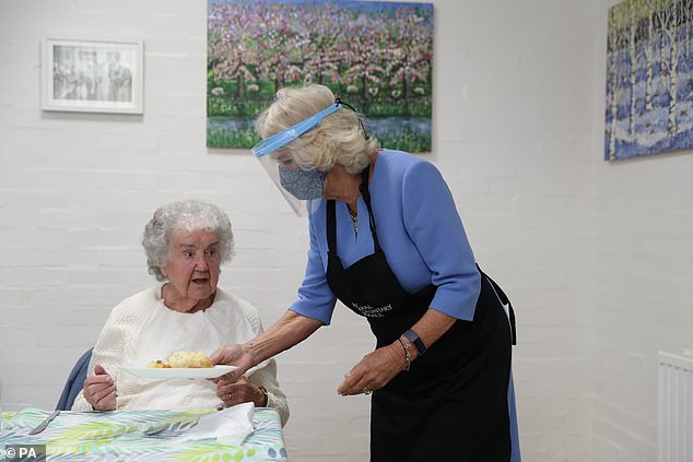 Duchess of Cornwall dons Burberry coat as she serves lunch to to volunteers in a plastic visor
