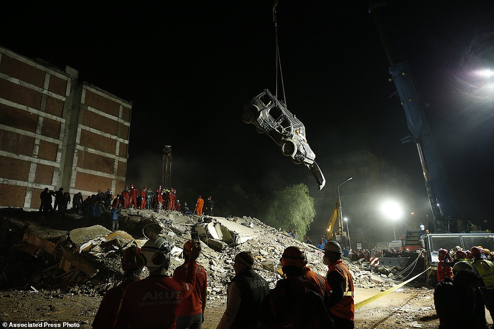Members of rescue services work on the debris of a collapsed building in Izmir, Turkey, Sunday