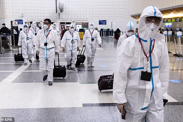 Airline crew members wear full hazmat suits as they arrive at LAX on Tuesday
