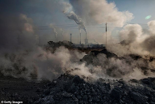 A staggering 59.8 percent of respondents say they are 'concerned about the carbon footprint of procreation'. Pictured: Steam and smoke from waste coal and stone rises after being dumped next to an unauthorized steel factory in Mongolia