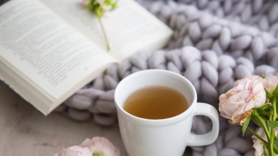 A cup with an infusion and a book