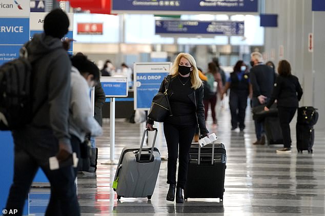 'Sometimes it's absolutely necessary, but to the extent possible, don't travel, don't congregate together,' Fauci said, A traveler wearing a mask walks through the O'Hare International Airport in Chicago on November 29
