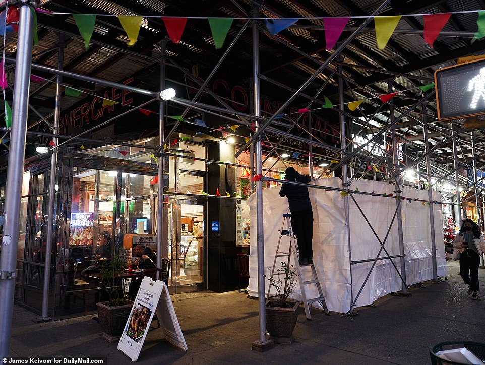 Employees at 94 Corner Cafe install a tarp in an outdoor seating area for diners on Tuesday