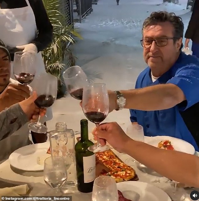 With indoor dining prohibited and outdoor dining set ups temporarily shut down, the restaurant employees were forced to sit on the sidewalk. They are seen sarcastically toasting with red wine as snow flurries fell