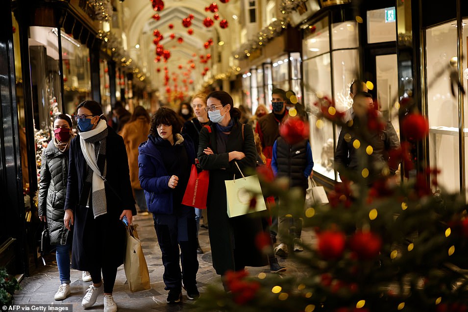 Pictured: Shoppers, some wearing a face mask or covering due to the COVID-19 pandemic, look at shop window displays inside a chrestmas-themed Burlington Arcade in London on December 19, 2020