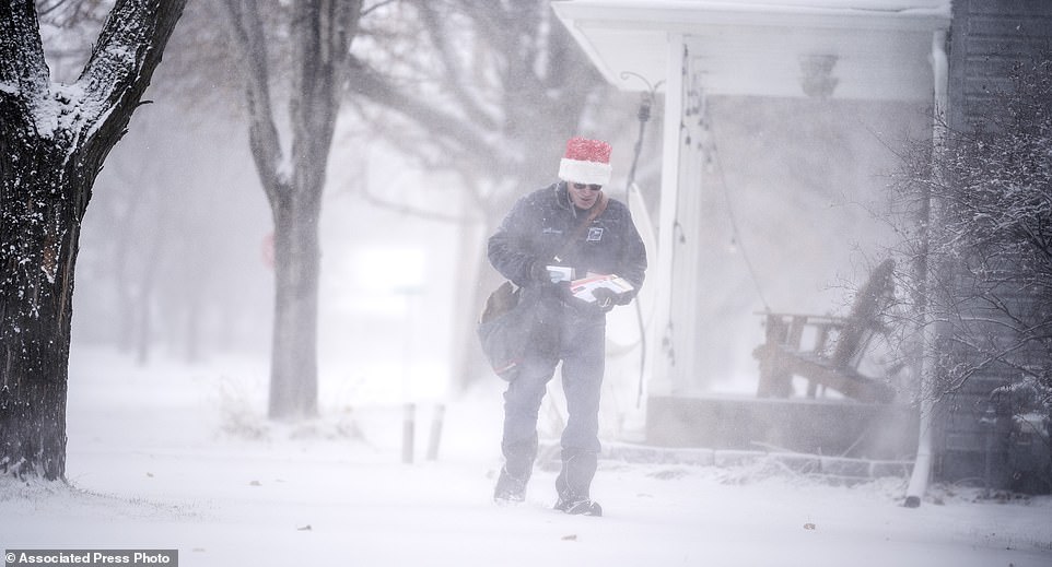 A mail carrier braves the blowing snow as blizzard-like conditions hit Osseo, Minnesota on Wednesday afternoon