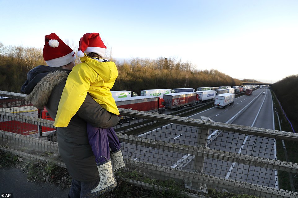 A mother and child wearing Christmas hats look at the line of trucks parked up on the M20, part of Operation Stack in Ashford, Kent