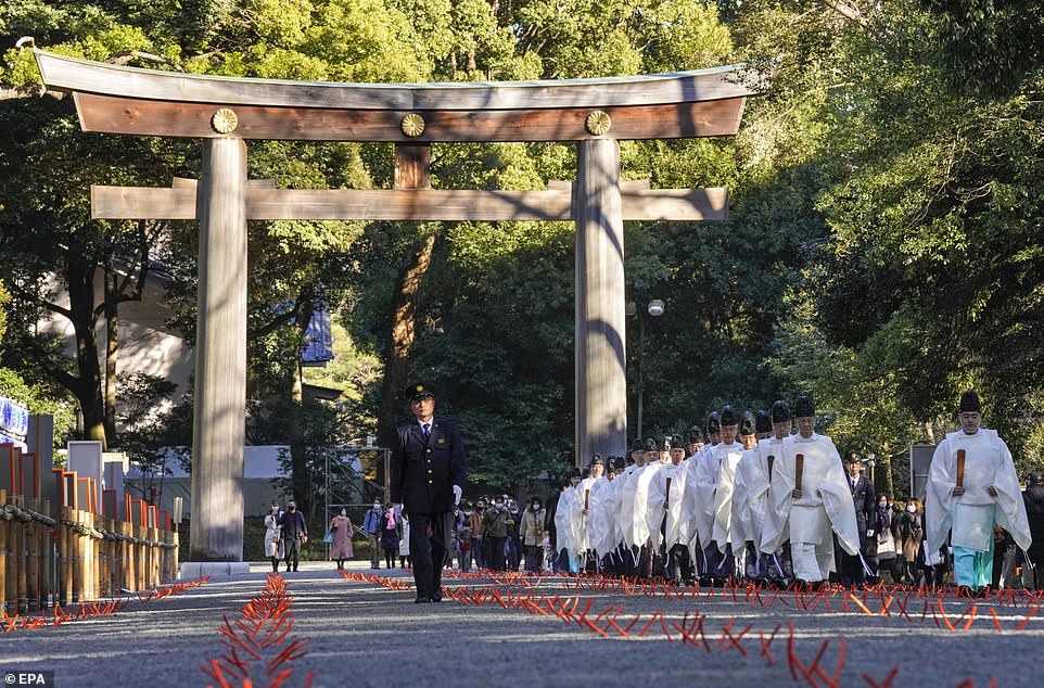 JAPAN: Shinto priests walk h a wooden gate in a ritual to purify sin and foulness on the final day of the year, at a shrine in Tokyo. Japan is suffering a resurgence of virus cases after generally keeping numbers fairly low
