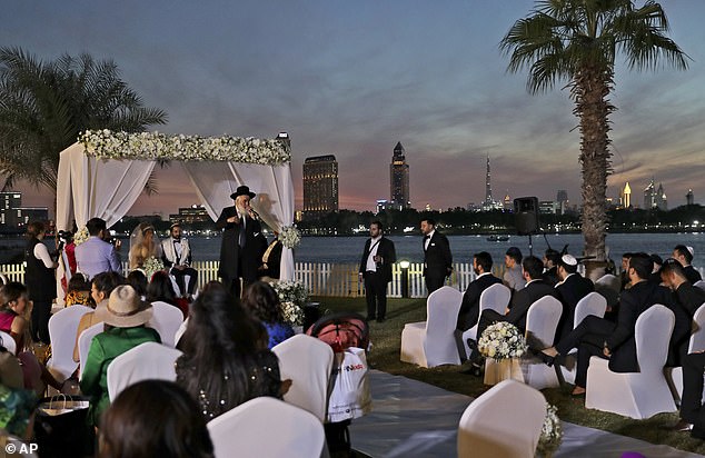 A rabbi officiates under a traditional Jewish wedding canopy during marriage ceremony of the Israeli couple Noemie Azerad, left sited under the canopy, and Simon David Benhamou, at a hotel in Dubai, United Arab Emirates, Thursday, December 17