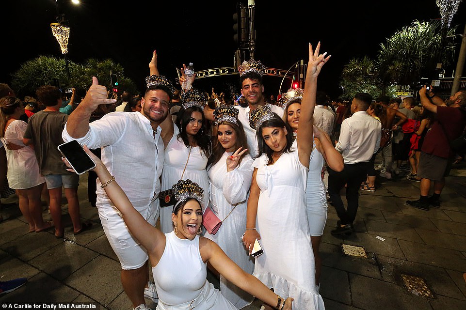 QUEENSLAND: A crowd of revellers dressed in matching white outfits and wearing 'Happy New Year' crowns pose for a photo