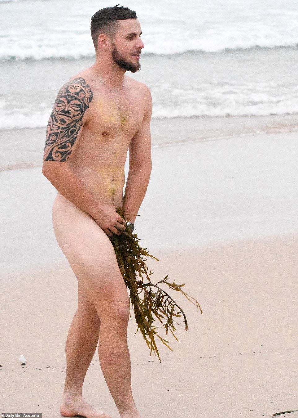A man covers his modesty with seaweed after stripping down to his birthday suit for a refreshing dip at Bondi Beach