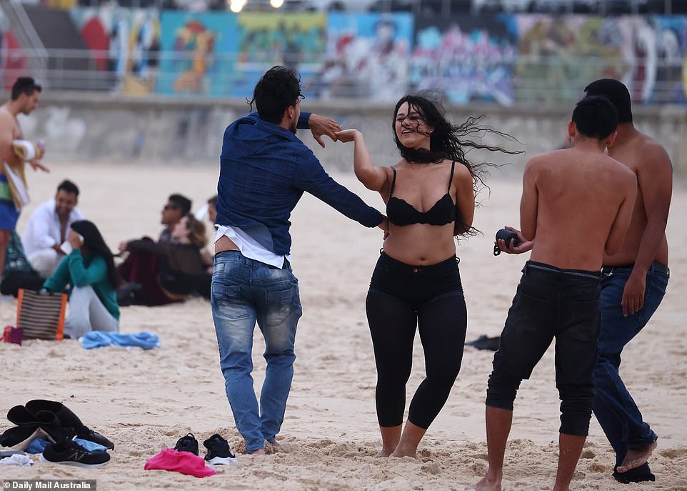 A man and a woman, joined by their friends, danced on the sand as they marked the start of January 1, 2021