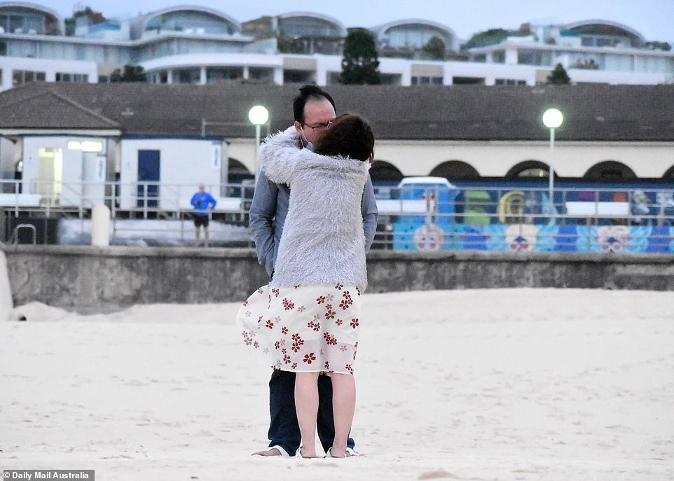A couple celebrate the New Year with a kiss as they stand on the sand at Sydney's most iconic beach