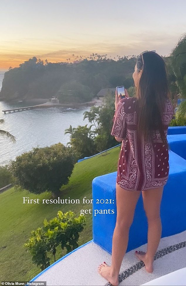 Sight for sore eyes: Olivia Munn was pictured looking out over a stunning scenic vista holding her phone and wearing a patterned shirt. 'First resolution for 2021: get pants,' she joked