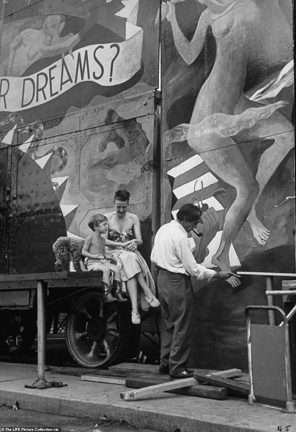 Burlesque dancer Gypsy Rose Lee sits with her son Erik Preminger in front of a mural designed by her husband, painter Julio de Diego during her carnival tour across America. Gypsy had amassed such a large fortune in burlesque that she purchased a palatial 26-room townhouse in the Upper East Side that was previously owned by the Vanderbilts and decorated it with paintings by Picasso, Chagall and Miro. She remodeled her bathroom in black and gold with a matching bathmat and toilet-seat cover made from mink