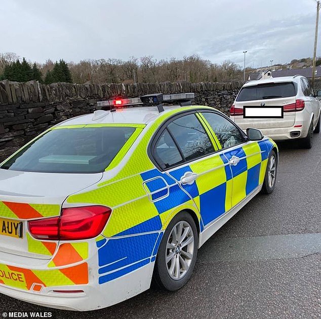 The top tier limits travel into Wales to essential only - such as for work - meaning travelling from England for a walk in against the law. Pictured: A police car stationed in Snowdonia