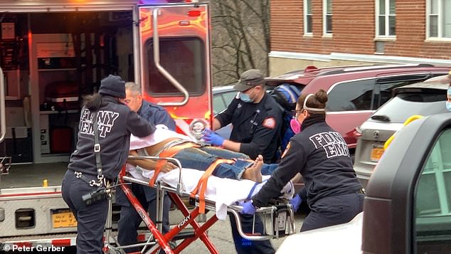 Fire crews are pictured loading the woman's body in to the back of an ambulance