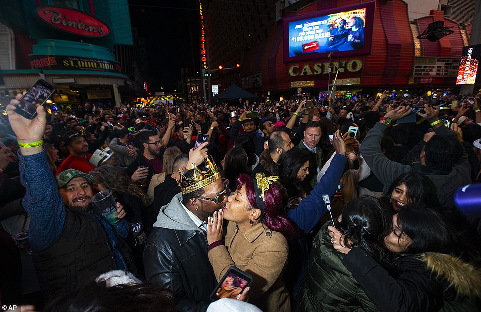A couple kisses while celebrating with a large crowd of hundreds - perhaps thousands - of partygoers on the Las Vegas Strip on New Year's Eve