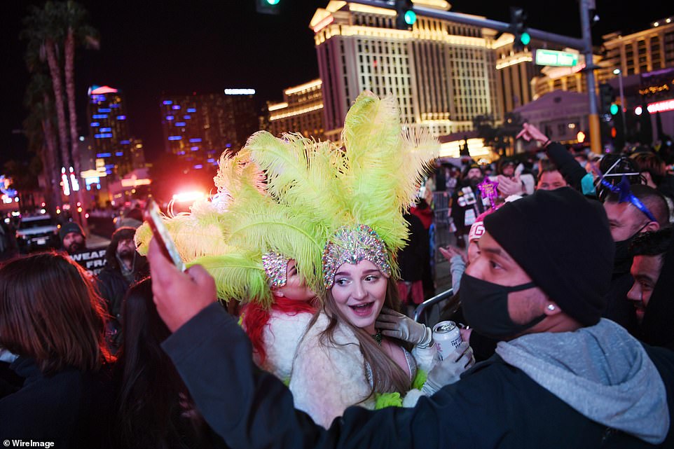 Revelers wearing costumes pose for selfies on the casino-lined Las Vegas Strip on New Year's Eve