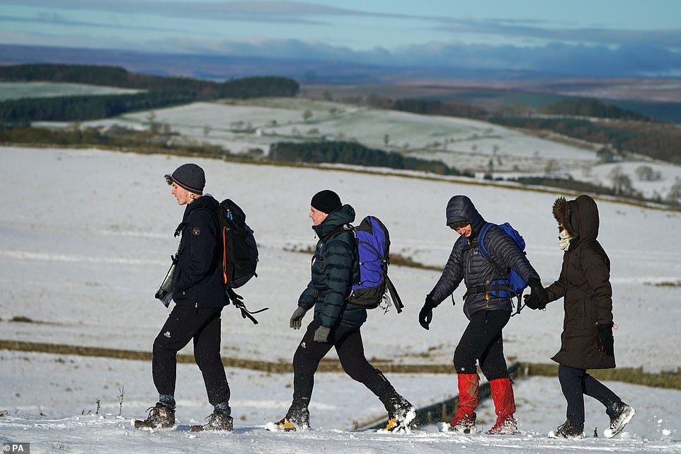 A family of hikers walk across Hadrian's Wall near Hexham as they enjoy a morning of exercise despite the snow