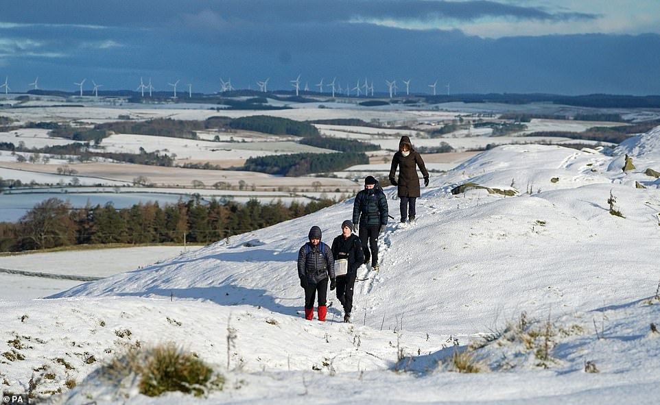 Hikers at Limestone Corner walk along a snow-covered Hadrian's Wall near Hexham, Northumberland