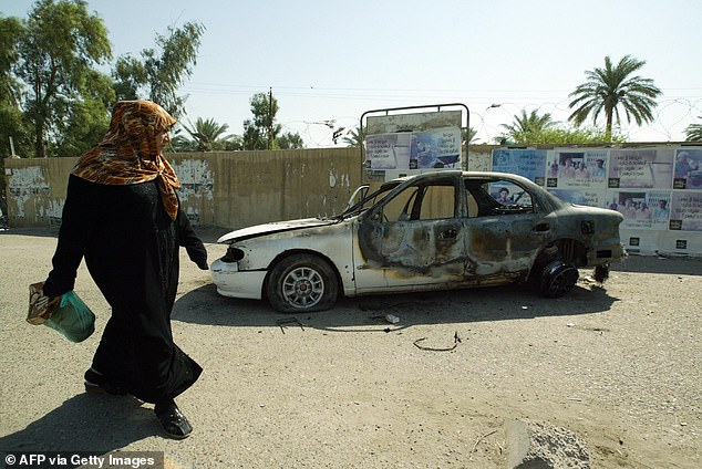 An Iraqi woman walks past a burnt car on the site where Blackwater guards who were escorting US embassy officials opened fire in the western Baghdad neighborhood of Yarmukh