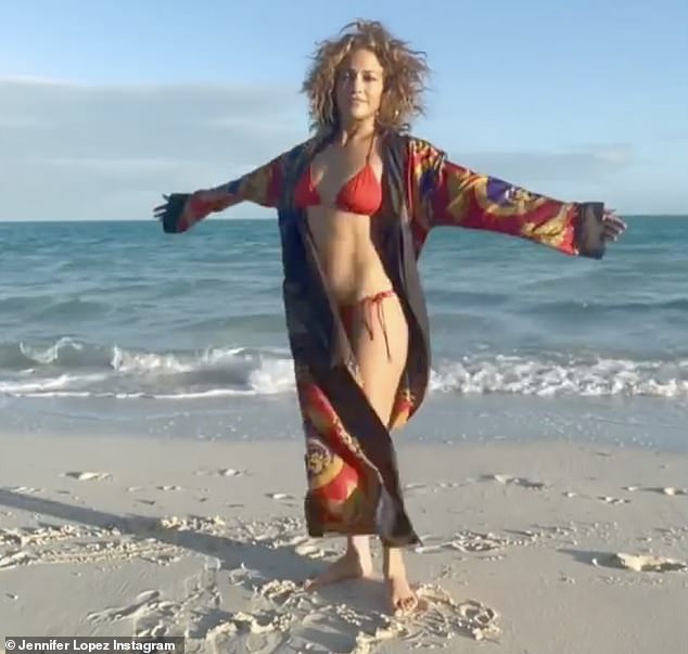 Not bad: The 51-year-old dancer, actress and singer posed in a bright red bikini while on a Florida beach, showing off her toned tummy and shapely legs, in a new video