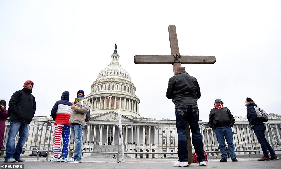 Jeremy LaPointe of Lumberton, Texas, holds a cross as he joins supporters of Trump gathered outside the US Capitol where Congress will meet to certify the electoral college vote for President-elect Joe Biden in Washington, DC, on Wednesday