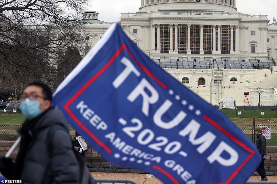 A stand is being erected at the base of the US Capitol as a pro-Trump supporter holds a flag, hours before Congress meets to certify the electoral college vote for President-elect Joe Biden in Washington, U.S., January 6, 2021. REUTERS/Jonathan Ernst