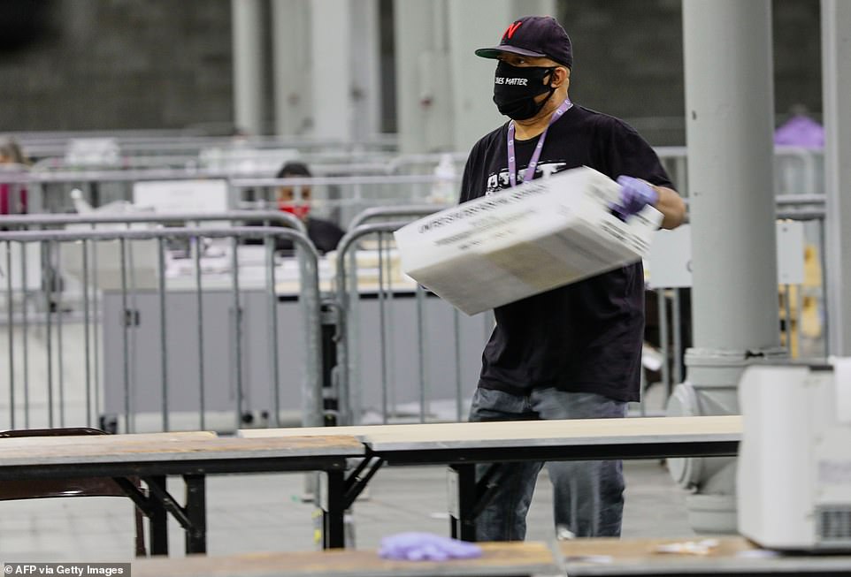 A worker carries a bin of ballots in for scanning at Georgia World Congress Center in Atlanta Tuesday night