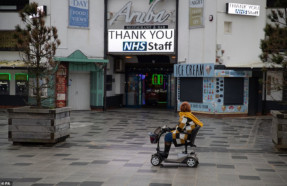 A person in a mobility scooter passes a 'Thank you NHS Staff' sign on the sea front on Bournemouth Beach in Dorset
